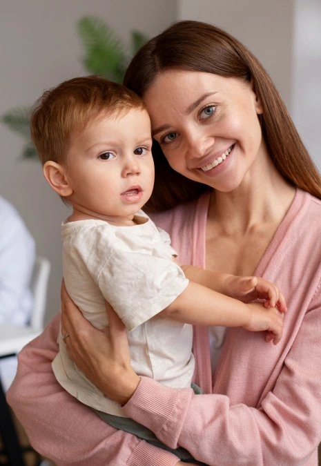 Kucağında küçük çocuğunu tutan gülümseyen anne